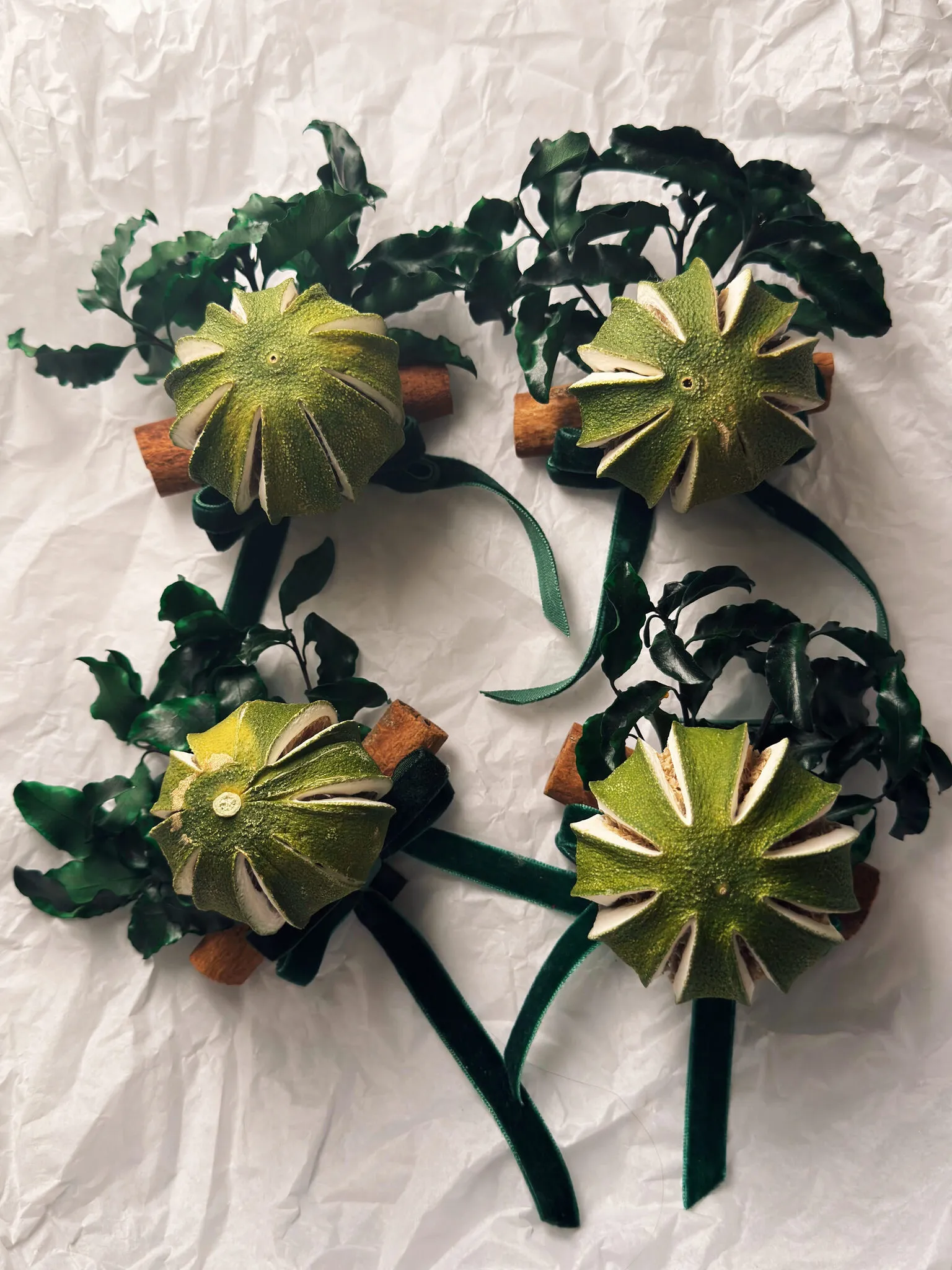 Natural Christmas baubles with dried green oranges, pittosporum foliage and cinnamon sticks with velvet ribbon handmade in London