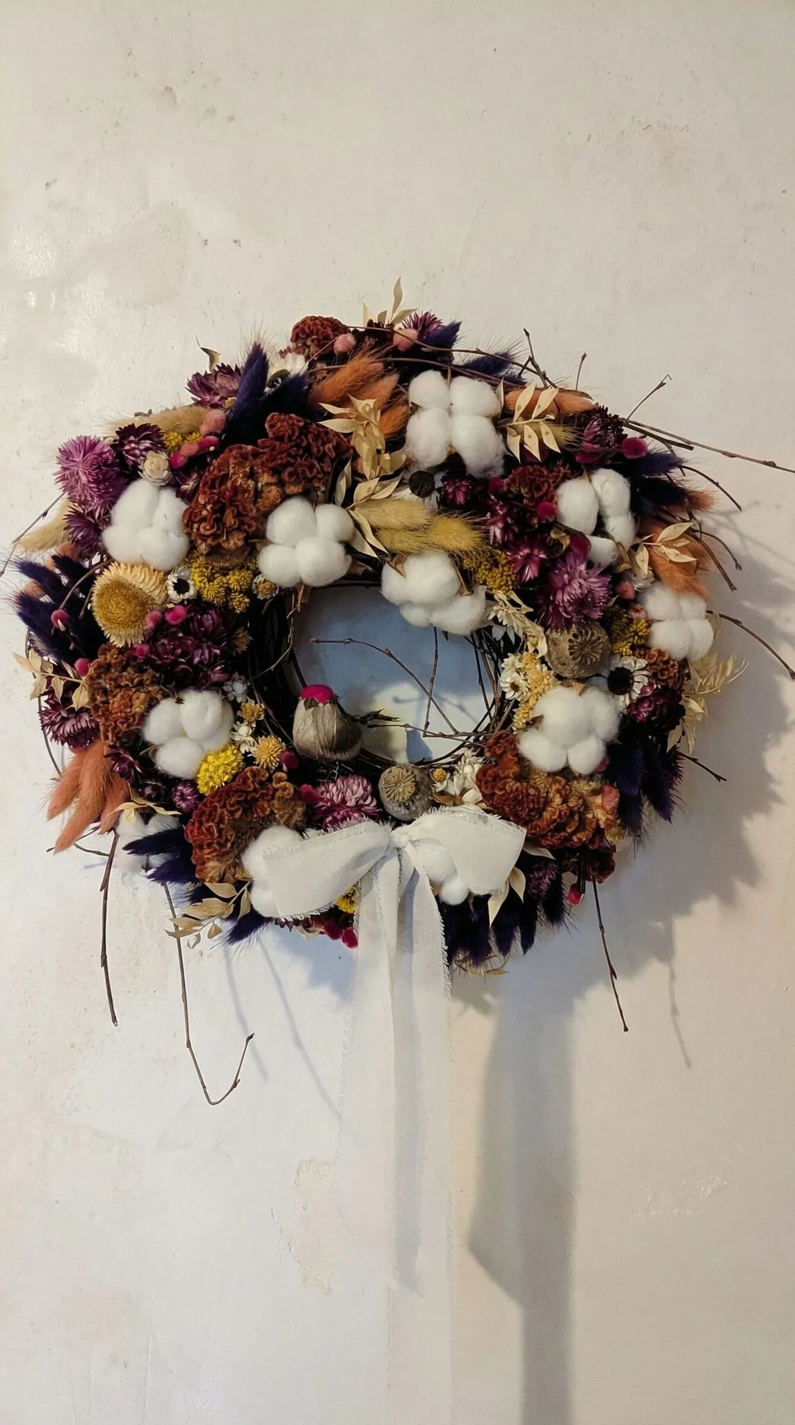 Natural Christmas wreath with cotton flowers and dried florals in rich winter colours handmade in London